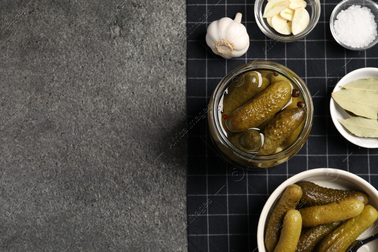 Photo of Tasty pickled cucumbers and spices on grey textured table, top view. Space for text