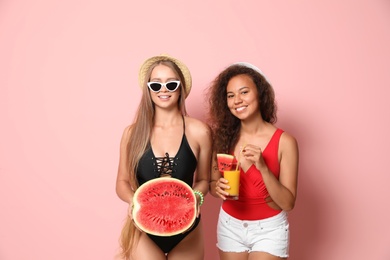 Beautiful young women in beachwear with watermelon on color background