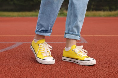 Photo of Woman wearing yellow classic old school sneakers on court outdoors, closeup