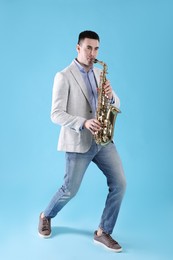 Photo of Young man playing saxophone on light blue background