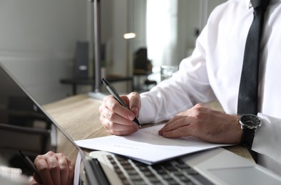 Businessman working with documents at wooden desk in office, closeup