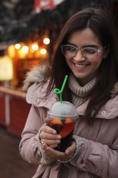 Woman with cup of mulled wine at winter fair