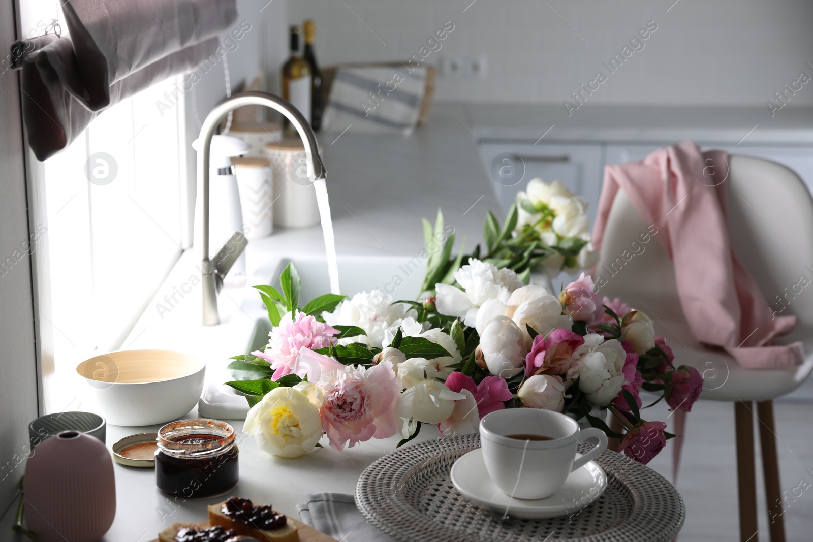 Photo of Beautiful peonies and breakfast on kitchen counter