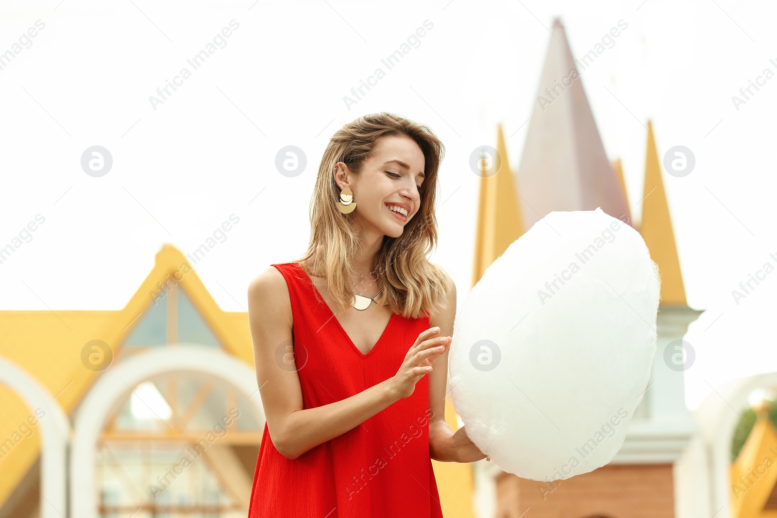 Photo of Happy young woman with cotton candy in amusement park