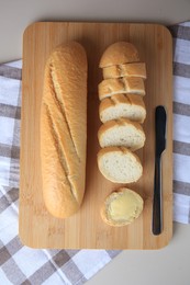 Photo of Whole and cut baguettes with fresh butter on table, flat lay