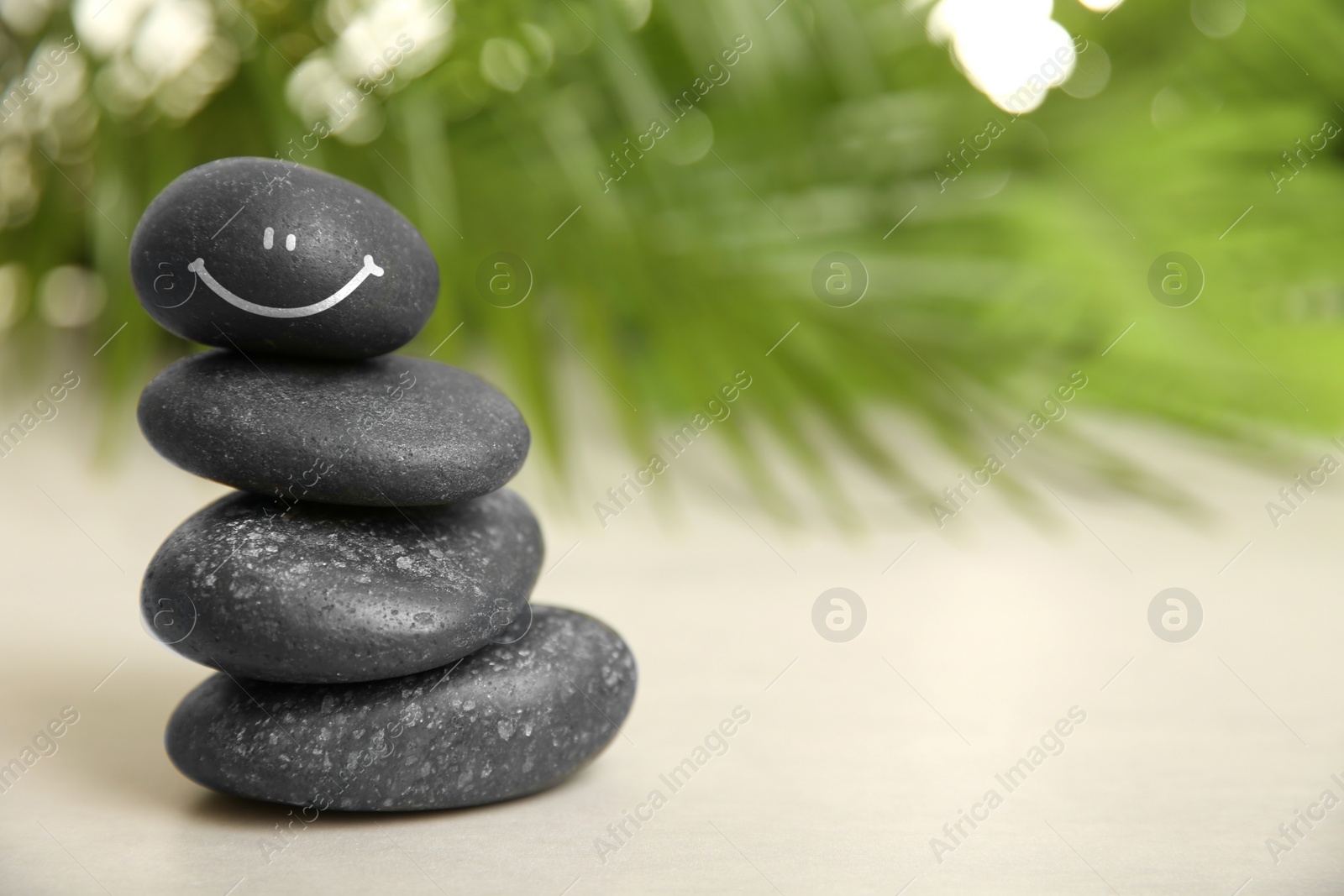 Image of Stack of stones with drawn happy face on white table, space for text. Be in harmony and enjoying your life