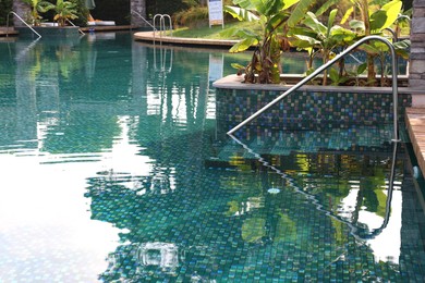 Outdoor swimming pool with metal rail and steps. Luxury resort