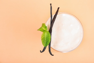 Glass with vanilla milk shake on color background, top view