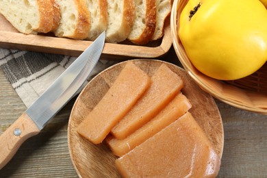 Photo of Tasty sweet quince paste, fresh fruit, bread and knife on wooden table, flat lay