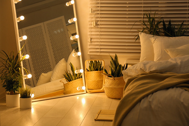 Stylish mirror with light bulbs in dark bedroom. Interior design