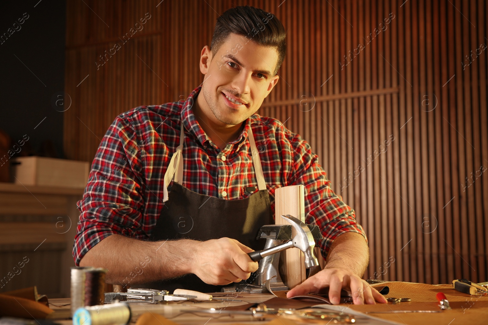 Photo of Man working with piece of leather at table in atelier