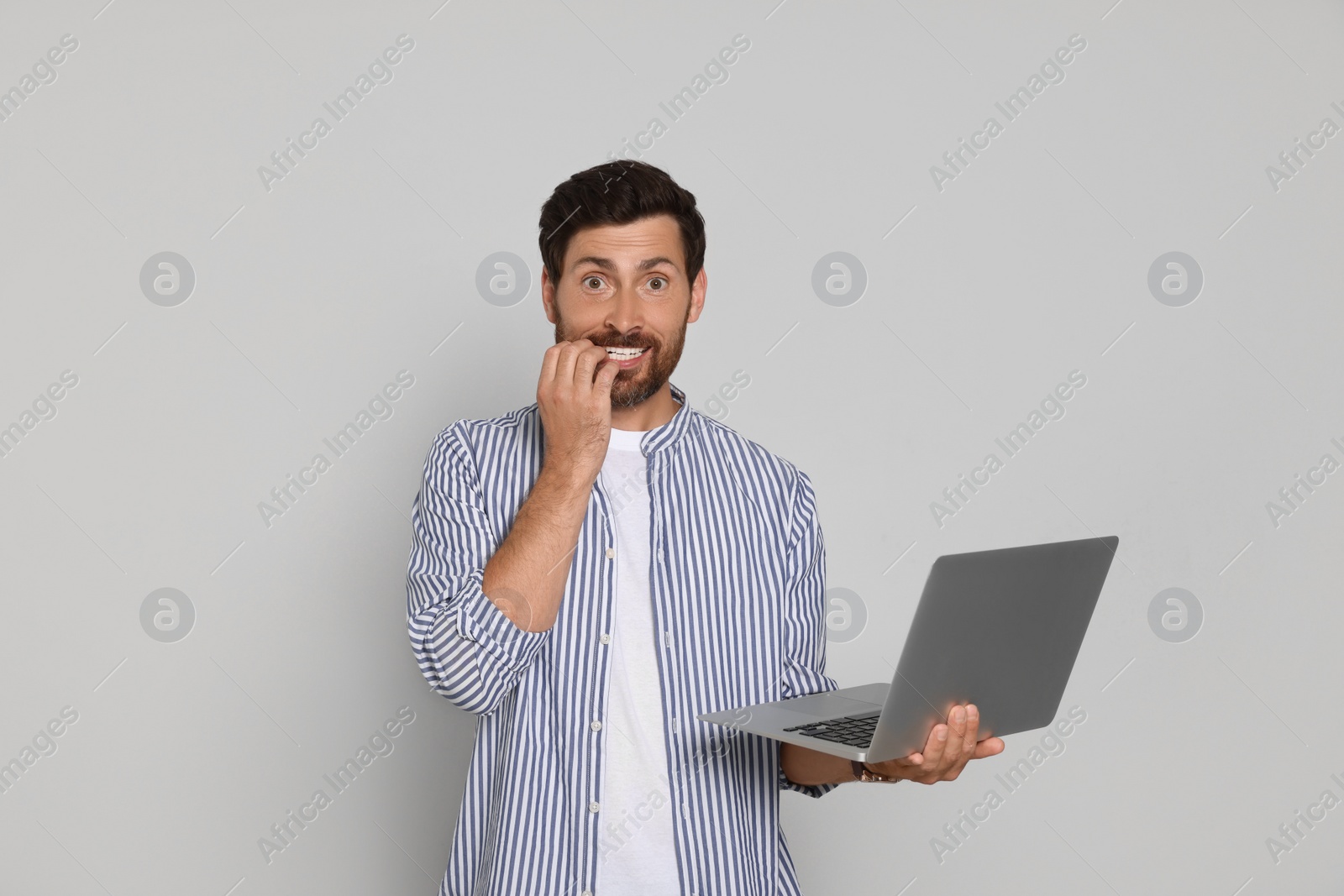 Photo of Emotional bearded man with laptop on light background