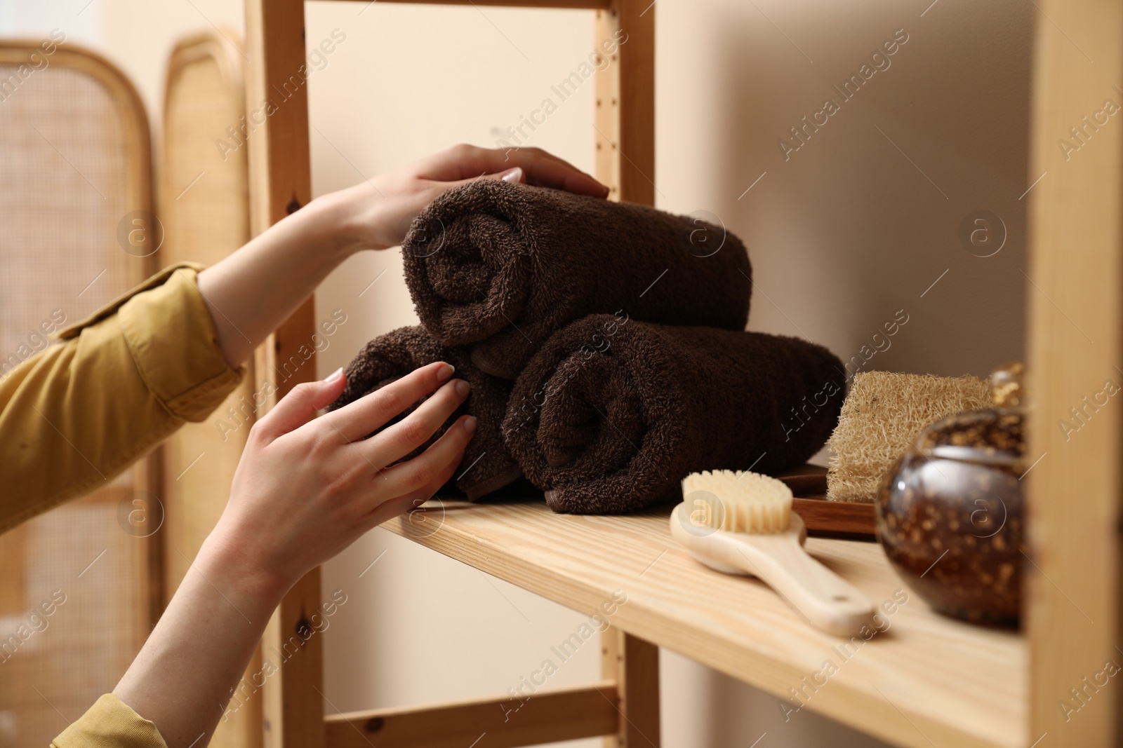 Photo of Woman taking rolled towel from shelf indoors, closeup