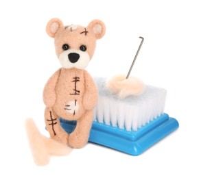 Photo of Needle felted bear, wool and tools isolated on white