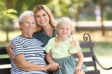 Photo of Woman with daughter and elderly mother on bench in park