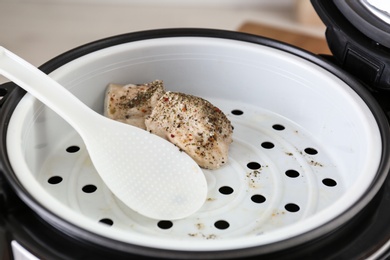 Photo of Delicious chicken with spices and spoon in multi cooker, closeup