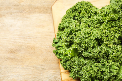 Fresh kale leaves on wooden table, closeup. Space for text