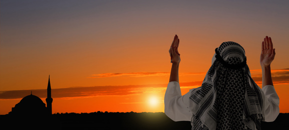 Muslim man praying outdoors at sunset. Banner design