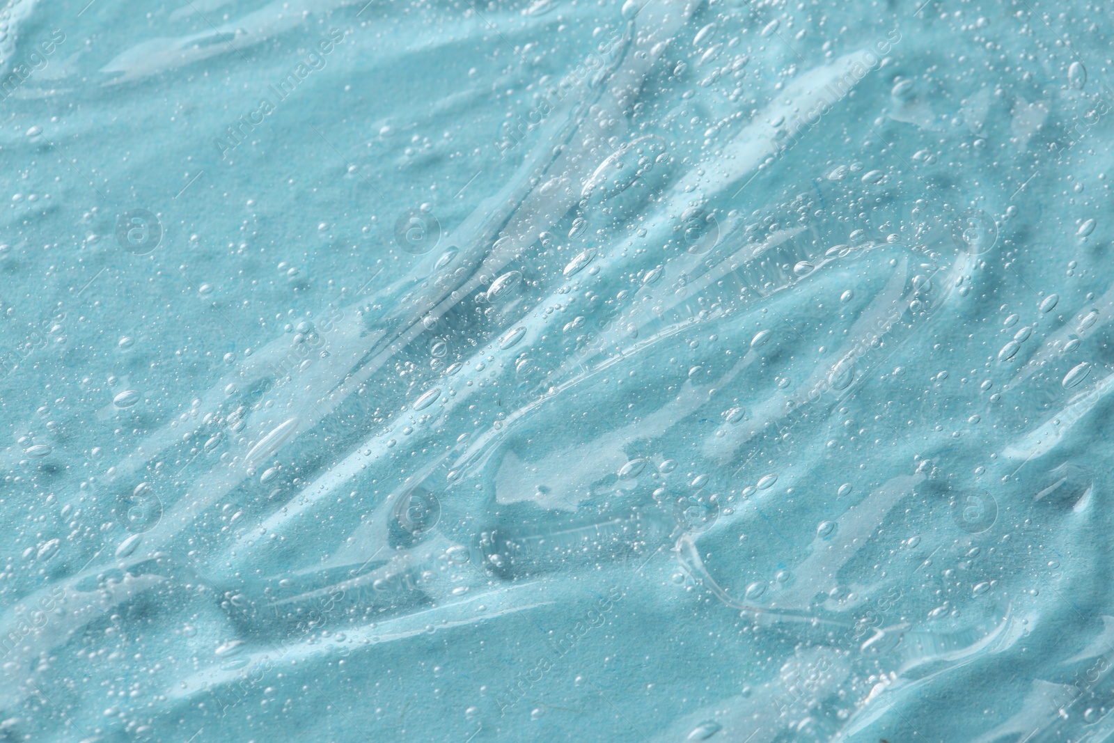 Photo of Clear cosmetic serum on light blue background, macro view