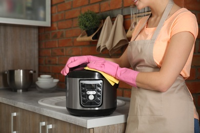 Young woman cleaning modern multi cooker in kitchen, closeup