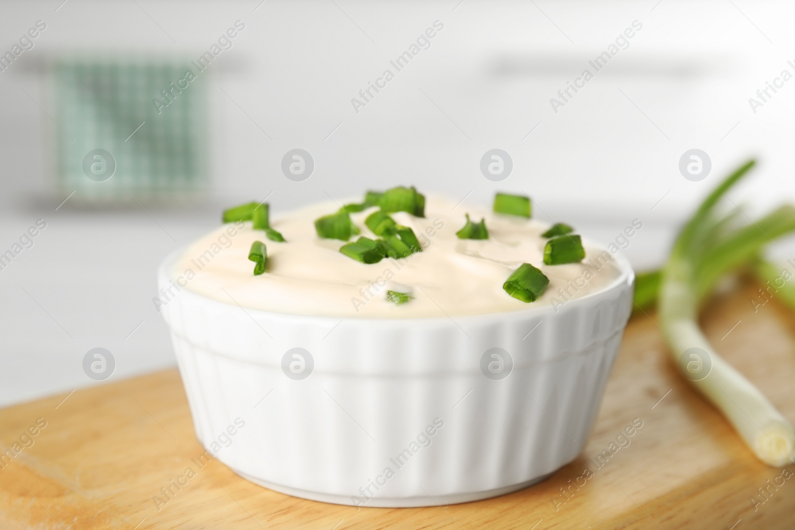 Photo of Fresh sour cream with onion on wooden board, closeup