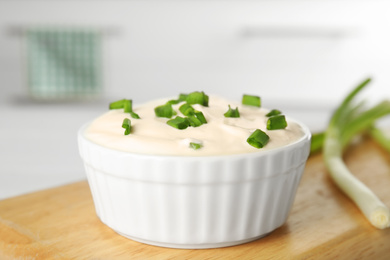 Photo of Fresh sour cream with onion on wooden board, closeup