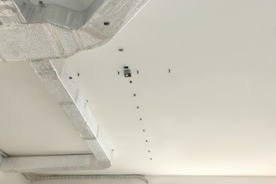 Photo of Connectors for wires and ventilation system on ceiling indoors