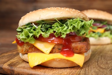 Photo of Delicious tofu burgers with fresh vegetables and sauce on wooden table, closeup