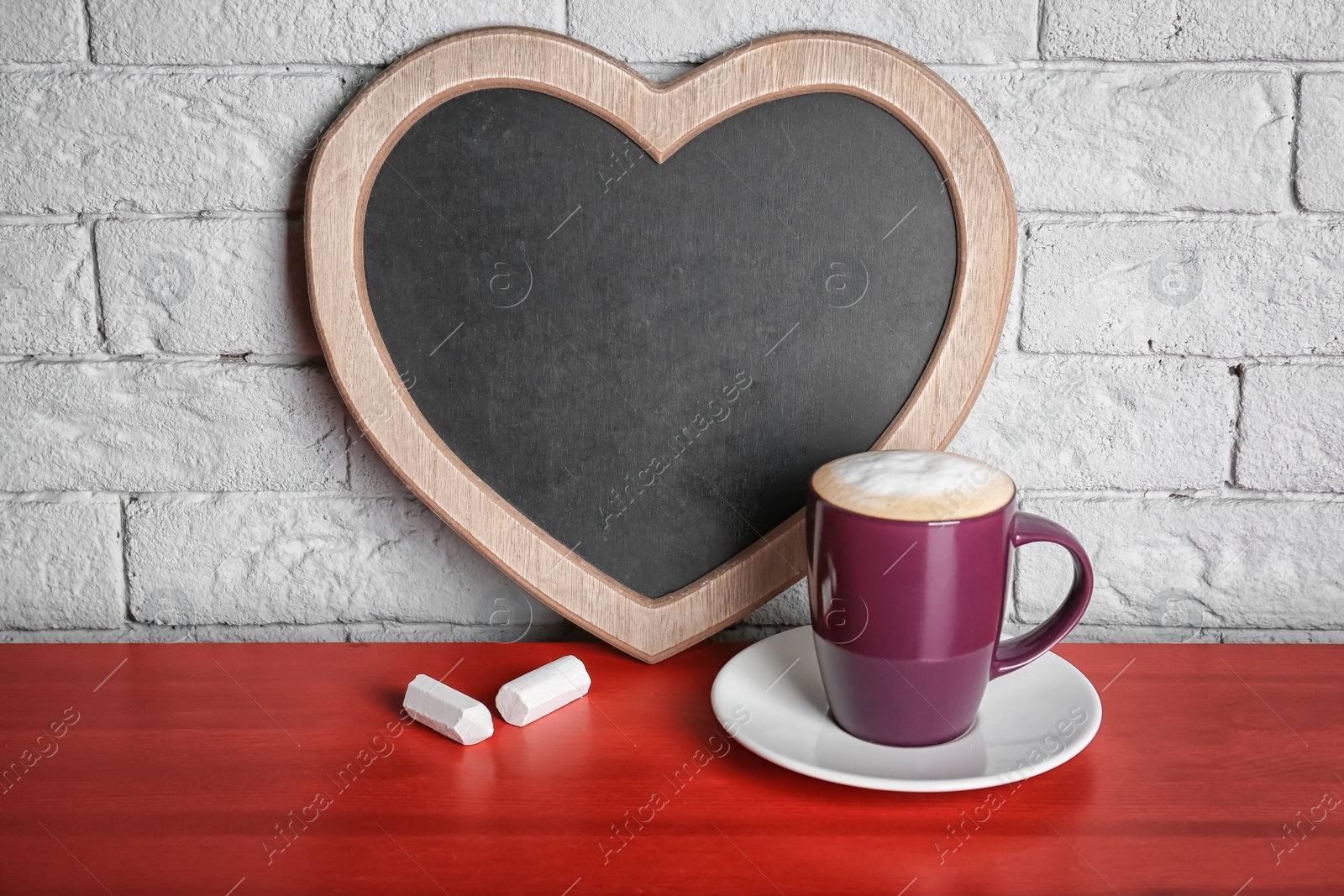 Photo of Cup of coffee on table near heart shaped chalkboard