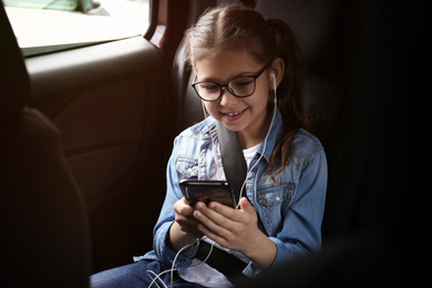 Cute little girl listening to audiobook in car