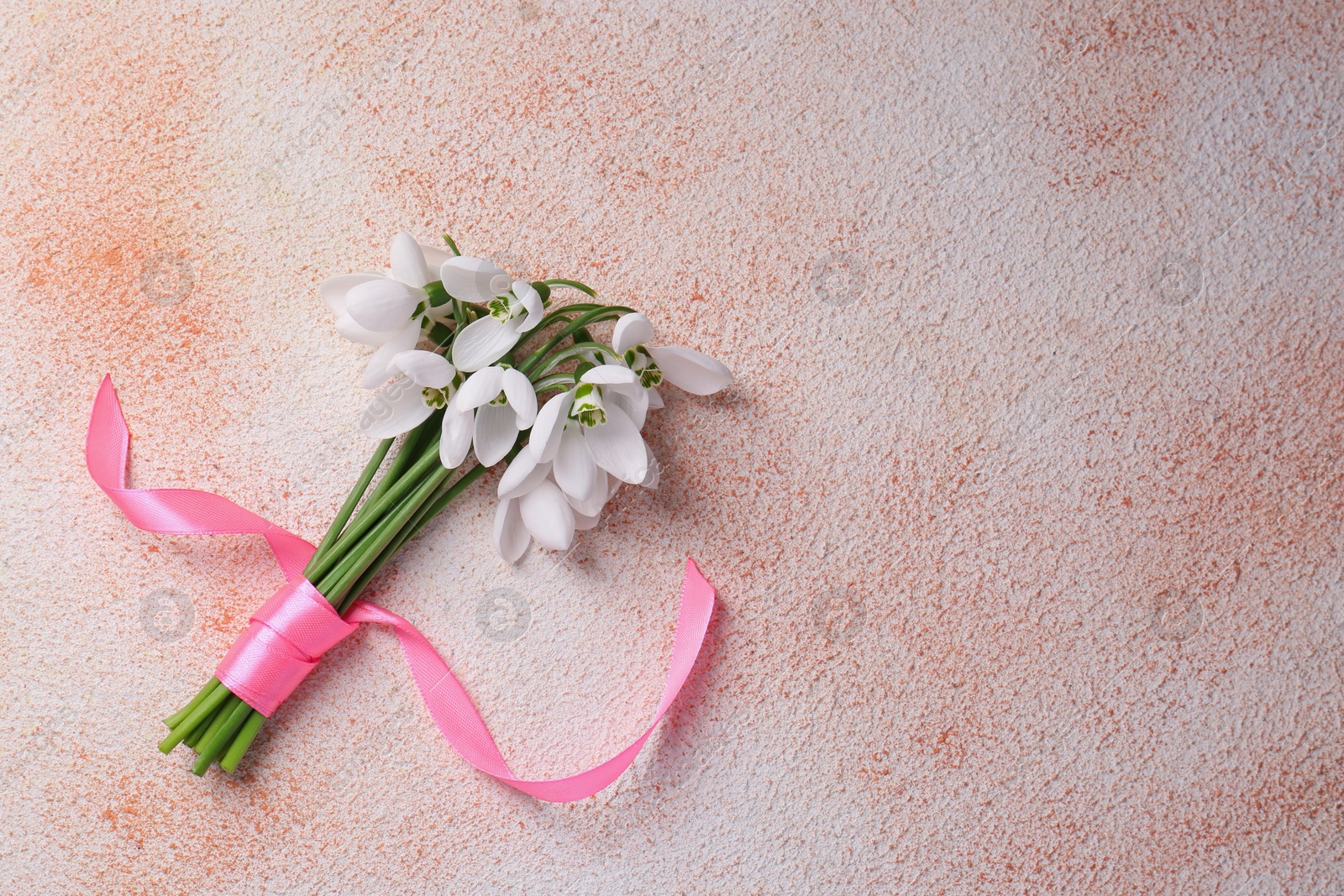 Photo of Bouquet of beautiful snowdrops on color textured background, top view. Space for text