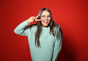 Photo of Young woman in warm sweater on red background