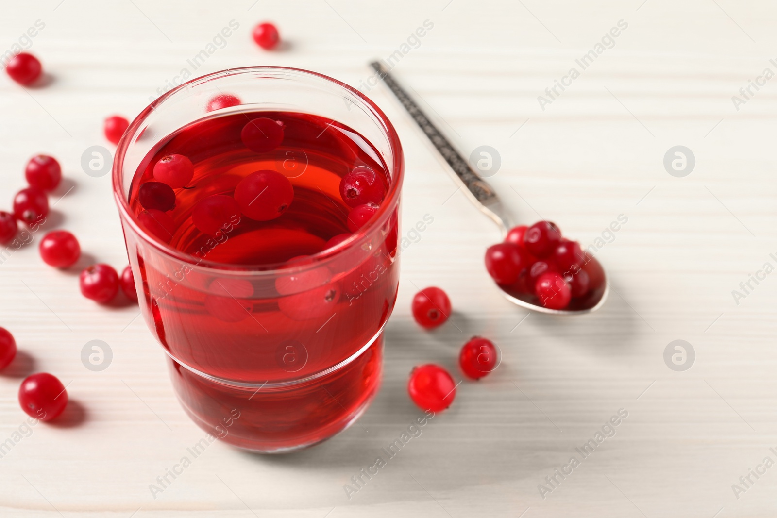 Photo of Tasty cranberry juice in glass and fresh berries on white wooden table, closeup. Space for text