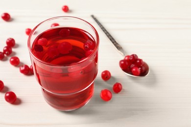 Tasty cranberry juice in glass and fresh berries on white wooden table, closeup. Space for text