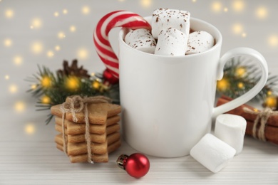 Photo of Composition with delicious marshmallow cocoa and Christmas decor on white wooden table