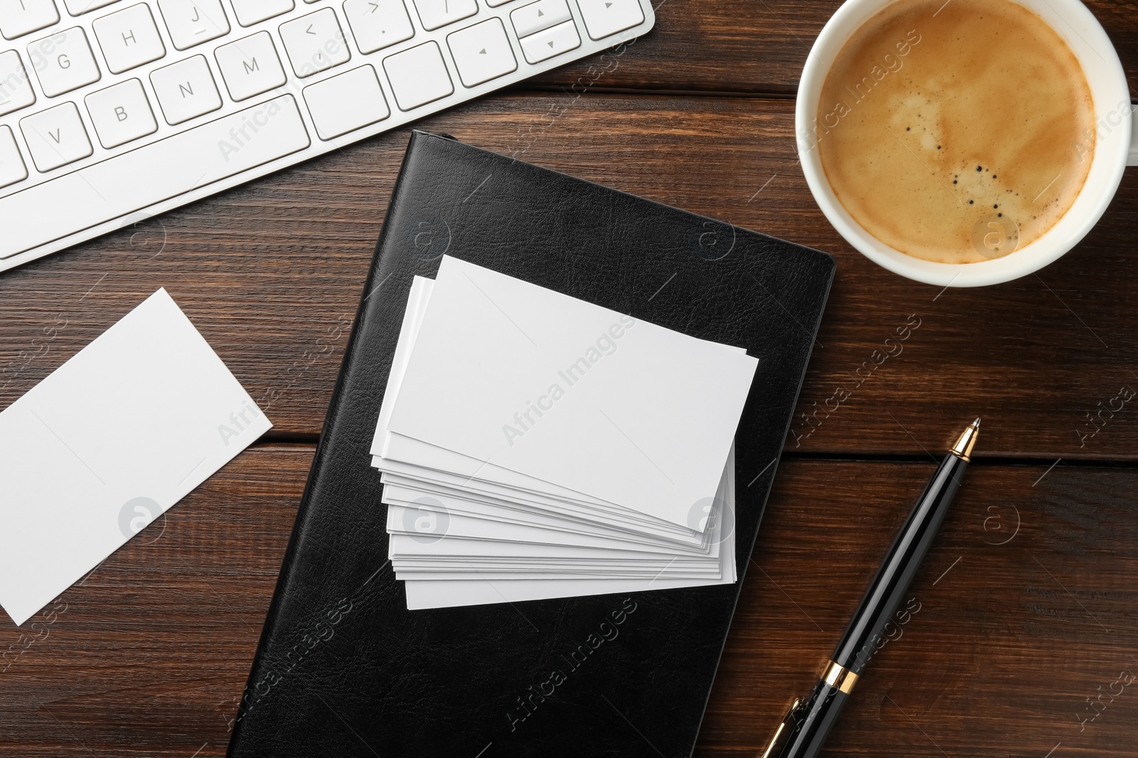 Photo of Blank business cards, coffee, keyboard and notebook on wooden table, flat lay. Mockup for design