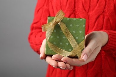 Christmas present. Woman holding gift box against grey background, closeup. Space for text