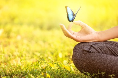 Woman meditating on green grass, closeup. Space for text