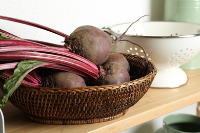 Photo of Raw ripe beets in wicker bowl on shelf indoors