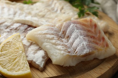 Photo of Fresh raw cod fillets on wooden board, closeup