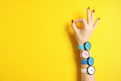 Photo of Woman wearing many bright wrist watches on color background, closeup view with space for text. Fashion accessory