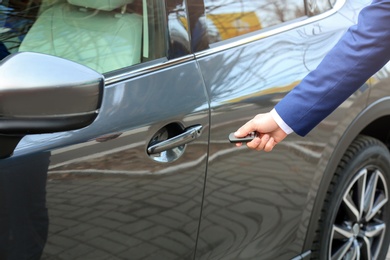 Photo of Closeup view of man opening car door with remote key