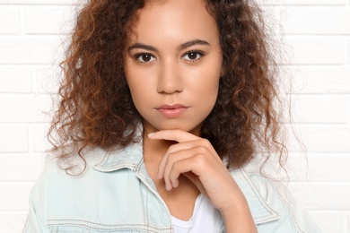 Young African-American woman with beautiful face near white brick wall, closeup