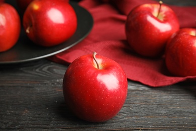 Photo of Ripe juicy red apples on black wooden table