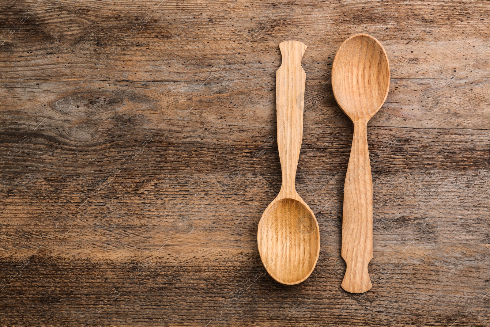 Photo of Clean empty spoons on wooden background, top view. Space for text