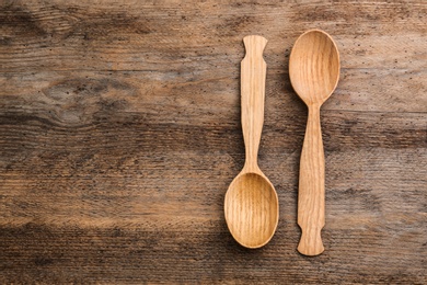 Clean empty spoons on wooden background, top view. Space for text