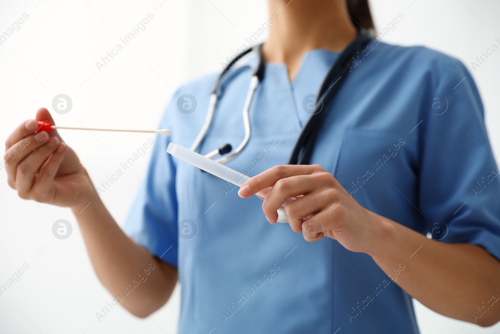 Photo of Doctor holding buccal cotton swab and tube for DNA test in clinic, closeup