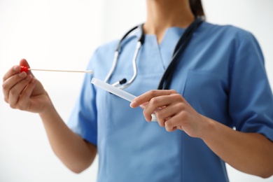 Doctor holding buccal cotton swab and tube for DNA test in clinic, closeup