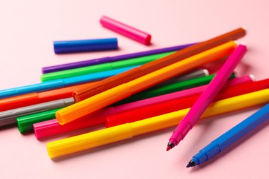 Photo of Many bright markers on pink background, closeup