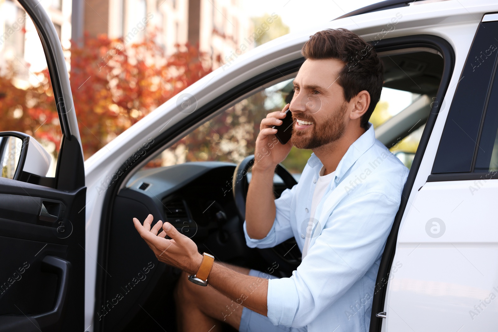Photo of Happy man talking on smartphone in modern car